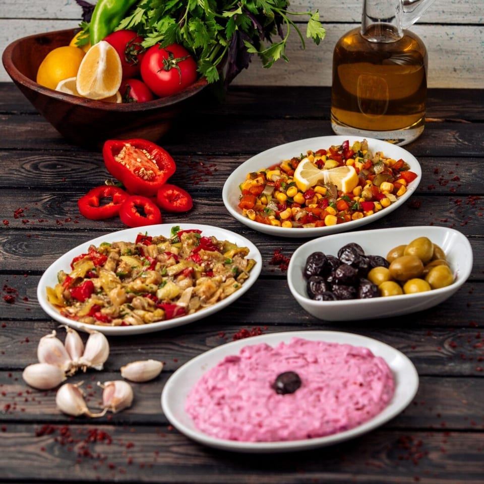 A wooden table with various Lebanese mezze dishes, including salads, olives, and a pink dip.
