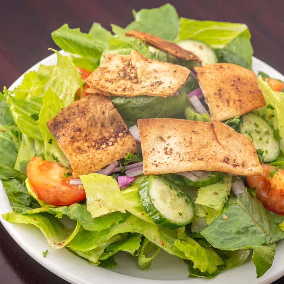 A vibrant Lebanese Fattoush salad with fresh greens, tomatoes, cucumbers, red onions, and crispy pita bread.