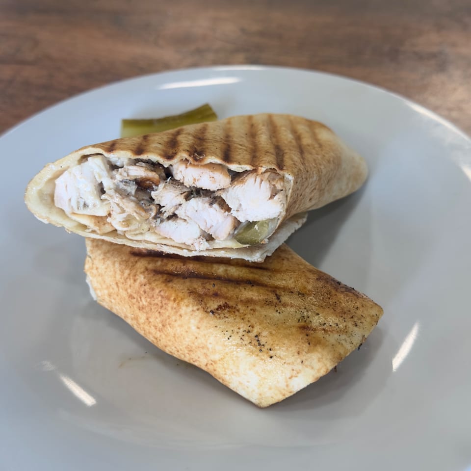 Grilled Lebanese chicken shawarma wrap, cut in half, revealing white meat and pickles on a plate.
